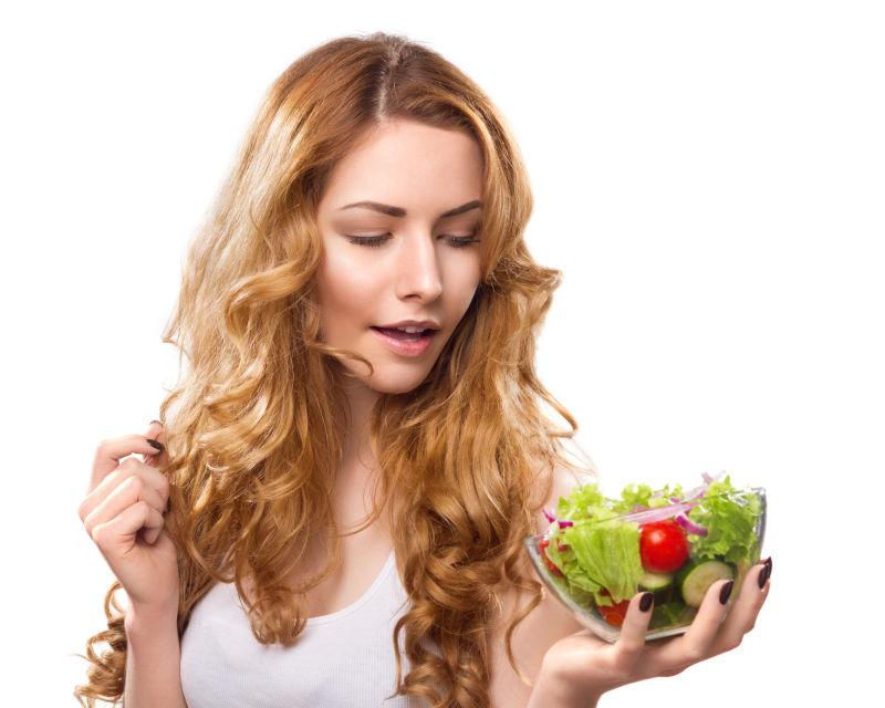 漂亮的金发女孩手拿蔬菜沙拉