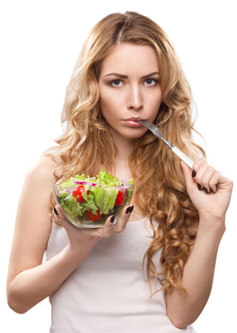 年轻的金发美女手拿沙拉