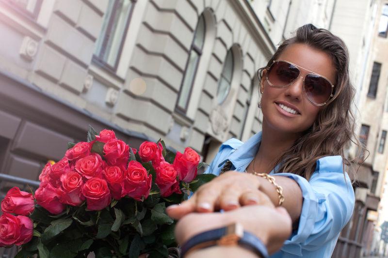 年轻美丽的女士手持美丽的玫瑰花束牵着丈夫的手跟着她