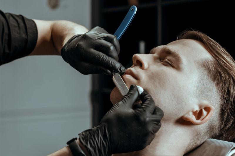 理发师修剪他年轻英俊的顾客的胡须