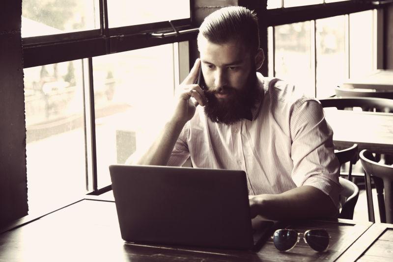 年轻的长胡子男子用笔记本电脑工作