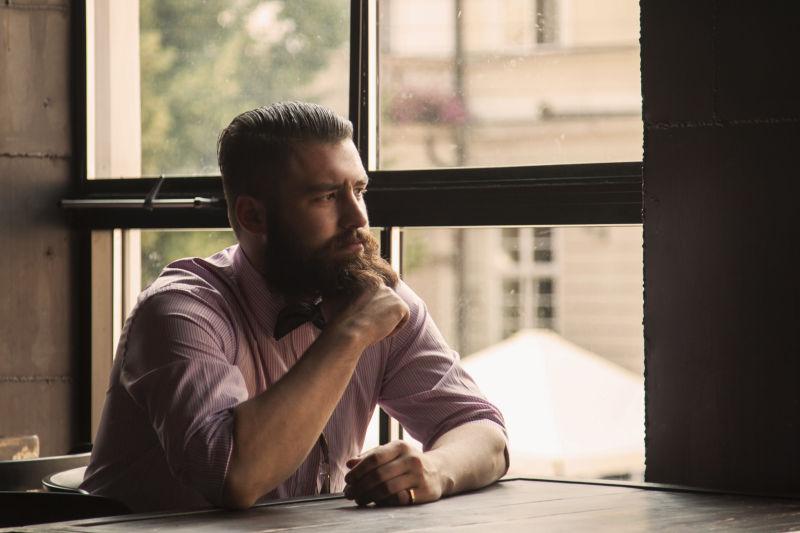 坐在桌子旁的年轻胡子男人