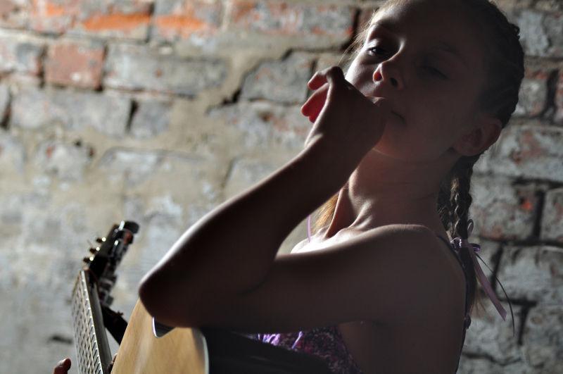 砖墙背景下弹吉他的少女