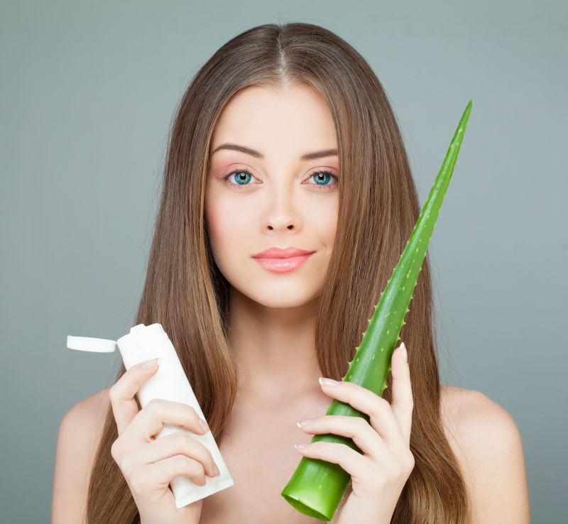 长发美女拿着芦荟和护肤品