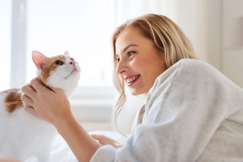 在床上逗弄猫咪的年轻美女