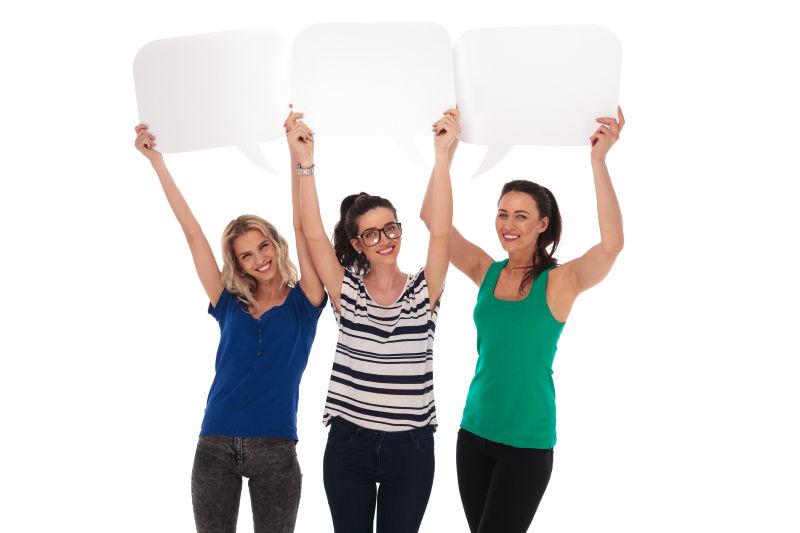 白色背景上举着空白气泡对话框的三个美女