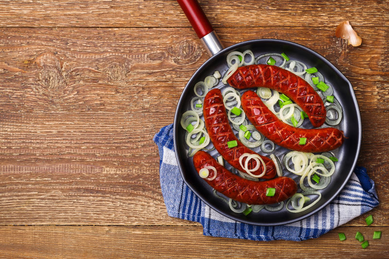 木桌煎锅上的洋葱和香肠