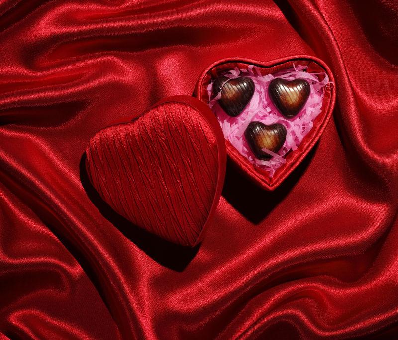 红色丝绸背景中心形盒子和巧克力