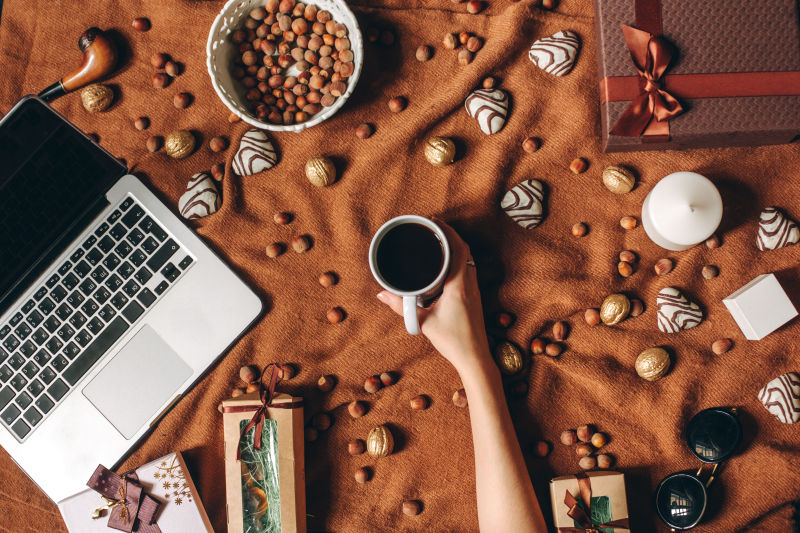 棕色麻布上的笔记本电脑坚果咖啡钢笔蜡烛礼品