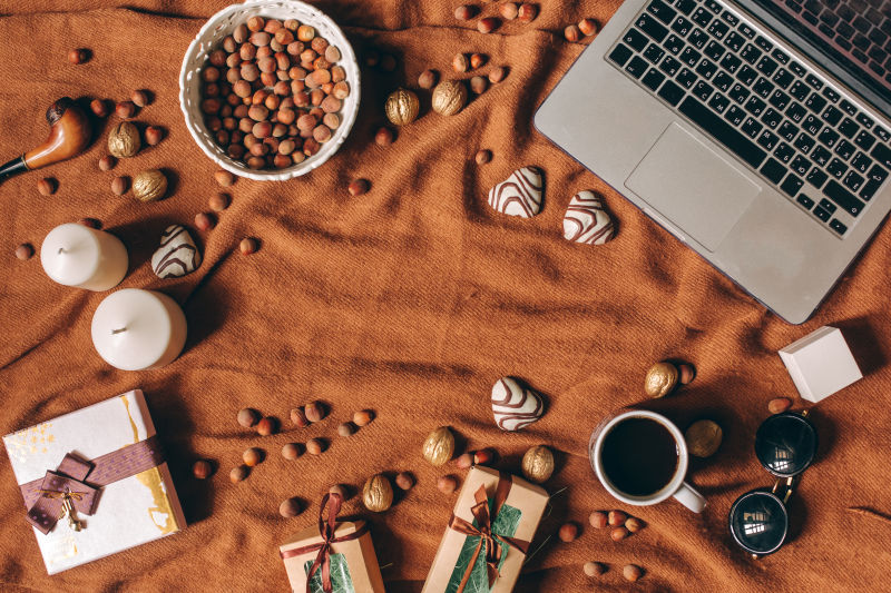 棕色麻布上的坚果笔记本电脑咖啡礼品蜡烛墨镜