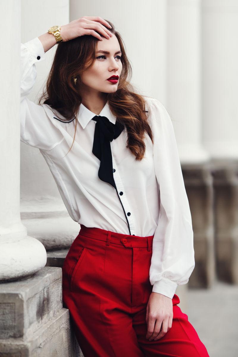 穿着红色裤子提着包包坐在飘窗台上的美女