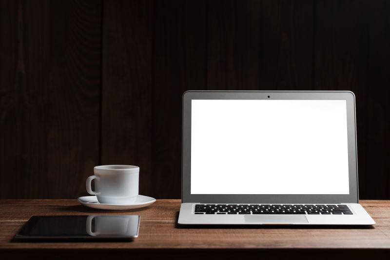 木桌上的咖啡杯笔记本电脑和平板电脑