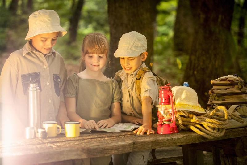 夕阳下一起研究地图的露营孩子们