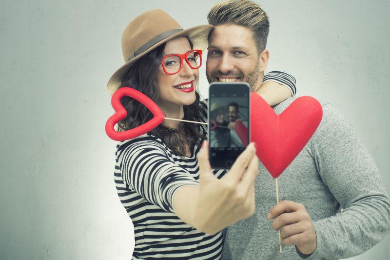 拿着红色心形的甜蜜情侣