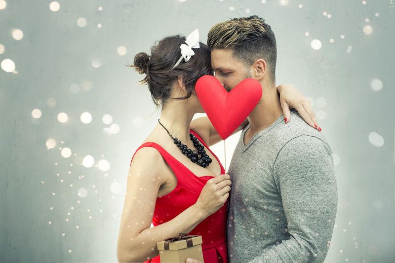 拿着红色心形接吻的夫妇