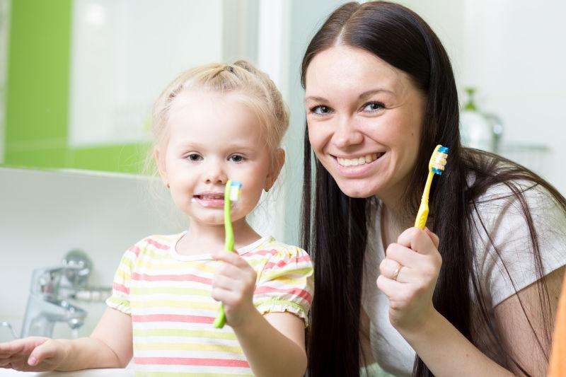 可爱的母女拿着牙刷