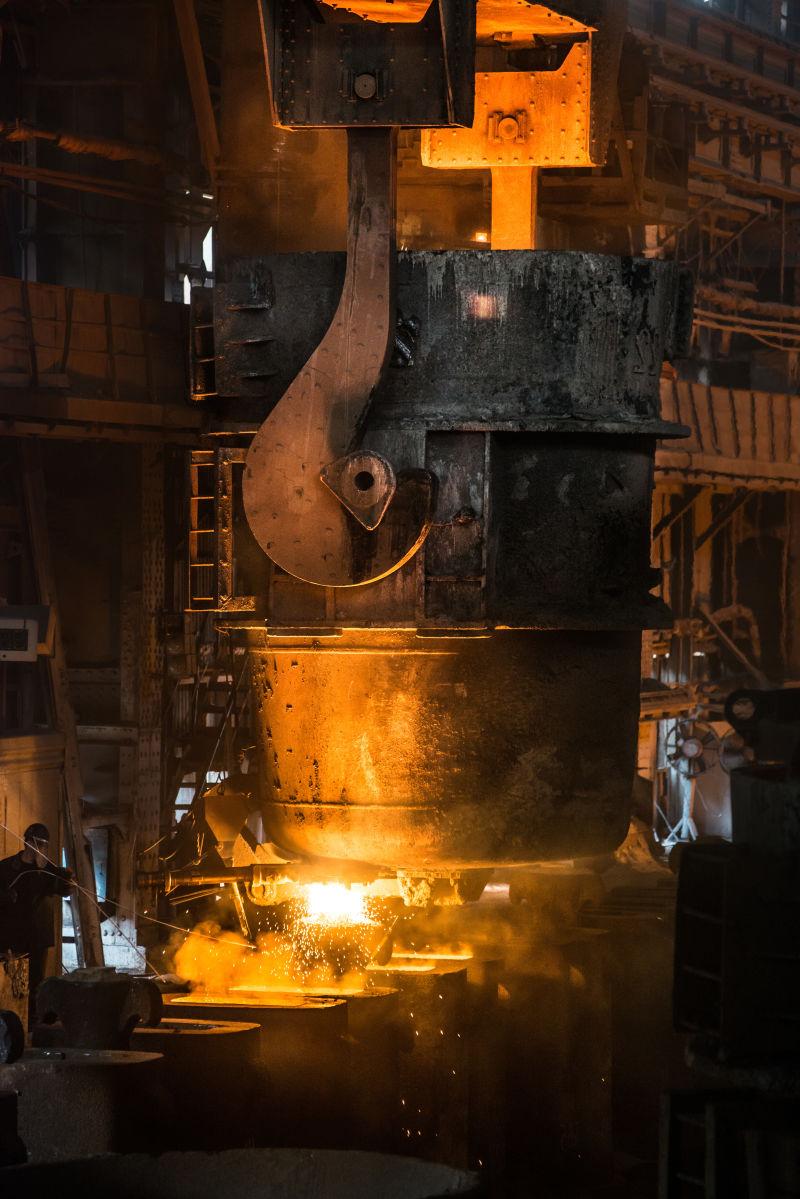 炼钢工人将液态金属倒进铸模中