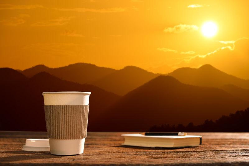 阳光下的木桌上的一杯咖啡和日记本