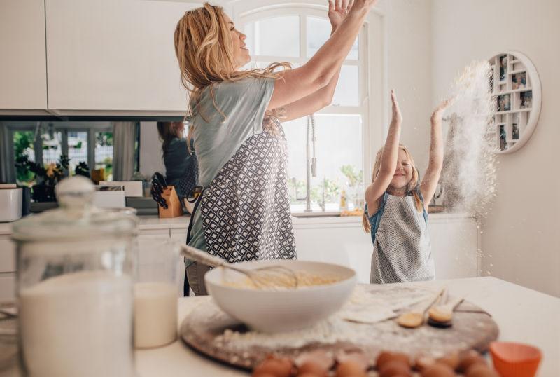 快乐的年轻妈妈和女儿在厨房里玩得开心