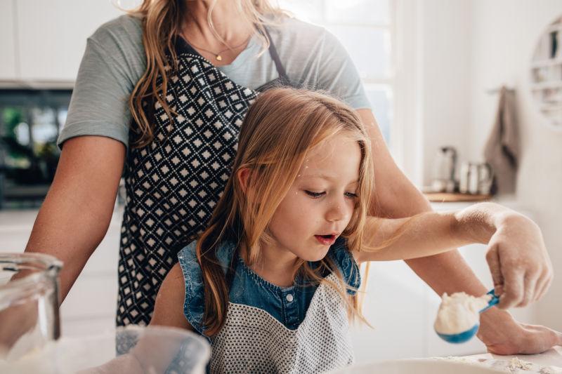 小女孩把厨房里的面糊和她妈妈混合在一起