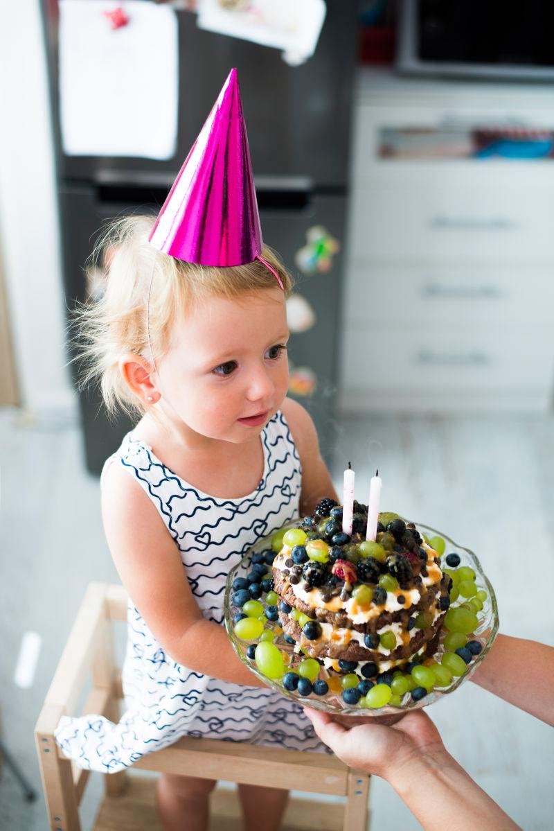 母亲用蜡烛给女儿生日蛋糕