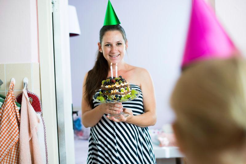 美丽的年轻微笑的母亲给她的女儿过生日生日蛋糕