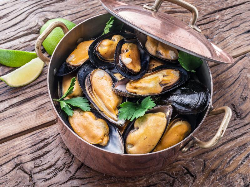 木纹理桌上的铜锅里的贻贝