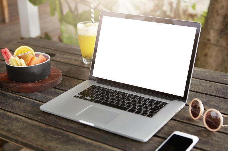 木桌上的水果饮料太阳镜和时尚女士的笔记本电脑