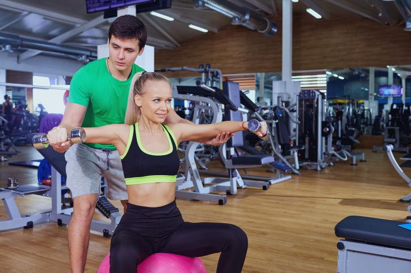 私人教练和女孩在健身房做哑铃锻炼