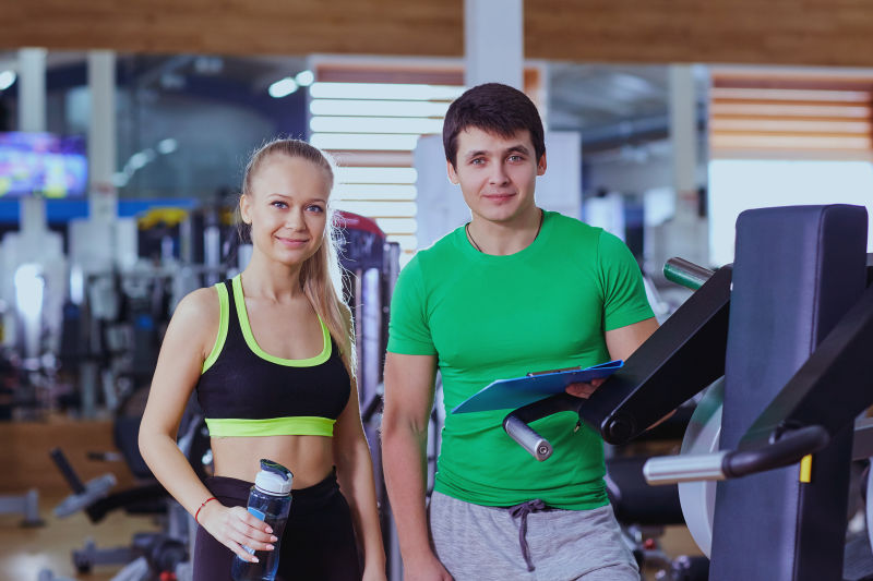 私人教练帮助女孩在体育馆里合照