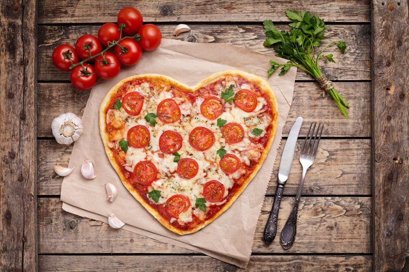 木制桌子背景中的心形披萨饼