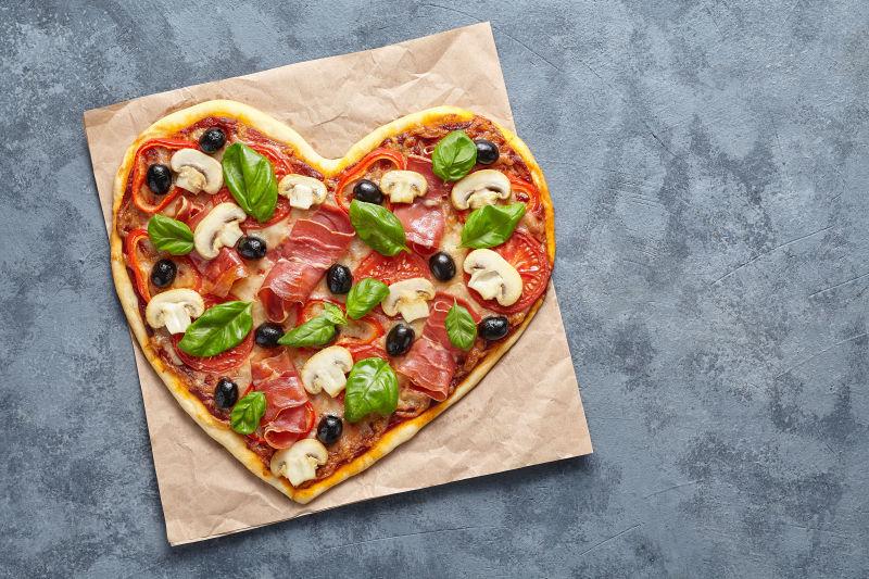 蓝色餐桌背景中的心形披萨饼