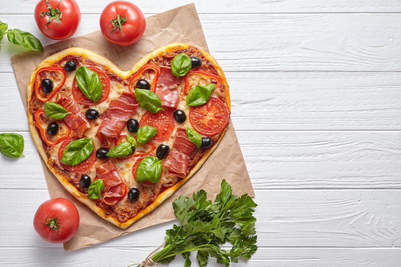 白色木桌子上的心形披萨饼