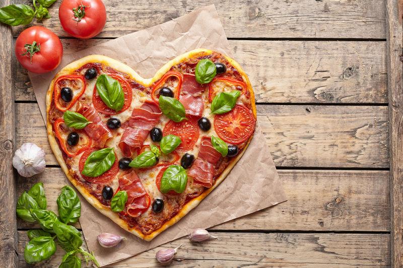 老式木桌上的心形披萨饼和西红柿