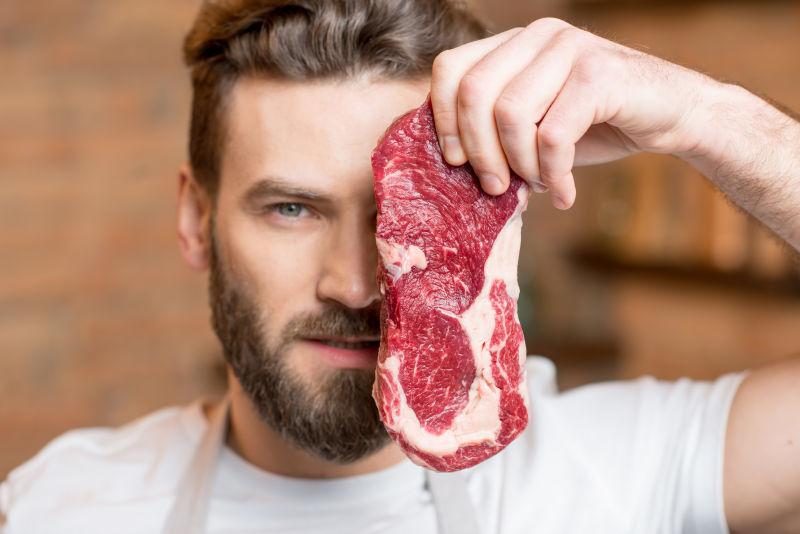 年轻的男子用生牛排遮住自己的脸