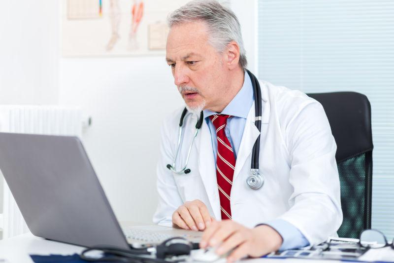 在他的笔记本电脑工作的高级医生