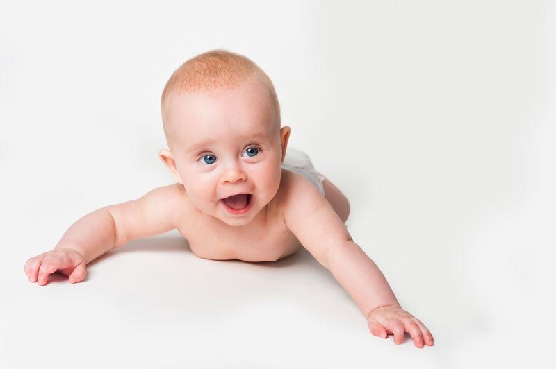 白色背景下趴着大笑的快乐的小婴儿