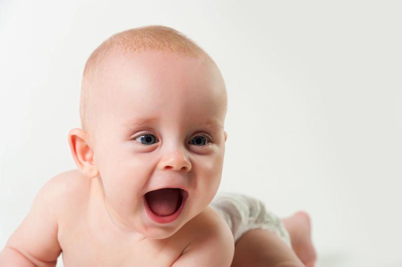 白色背景下张着嘴笑的女婴儿