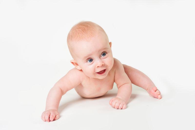 白色背景下向前爬行的微笑的可爱的小宝宝