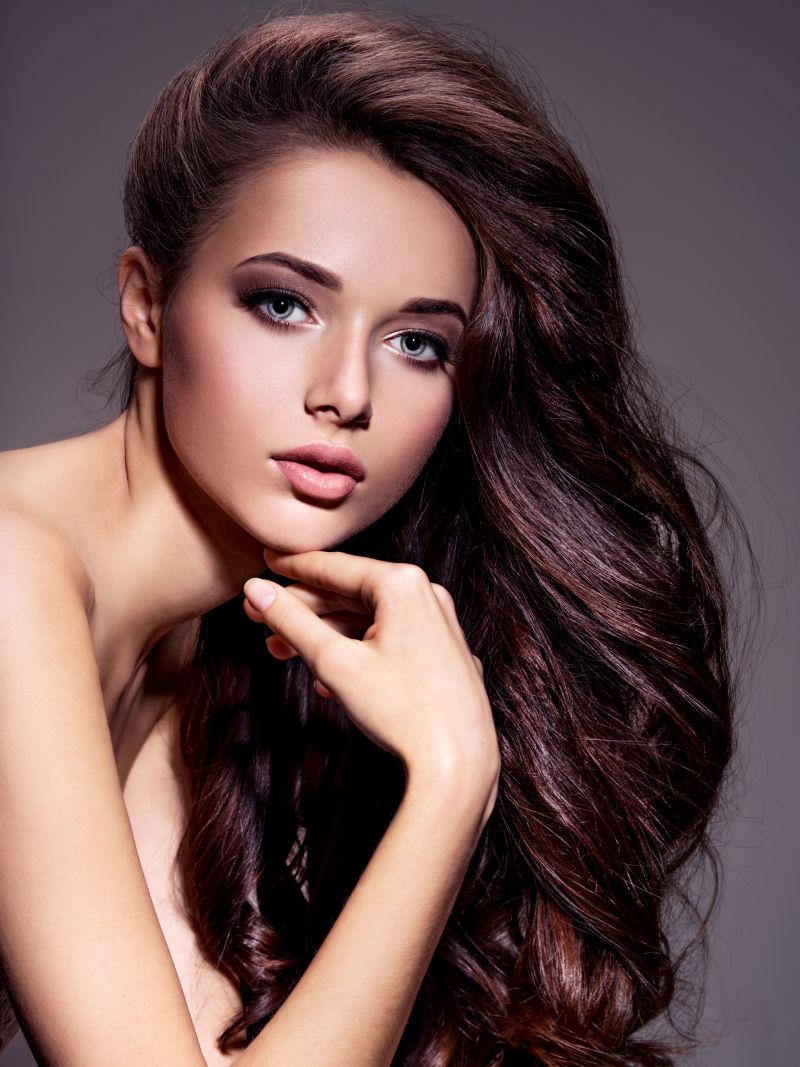 完美妆容的长棕色头发的年轻女人