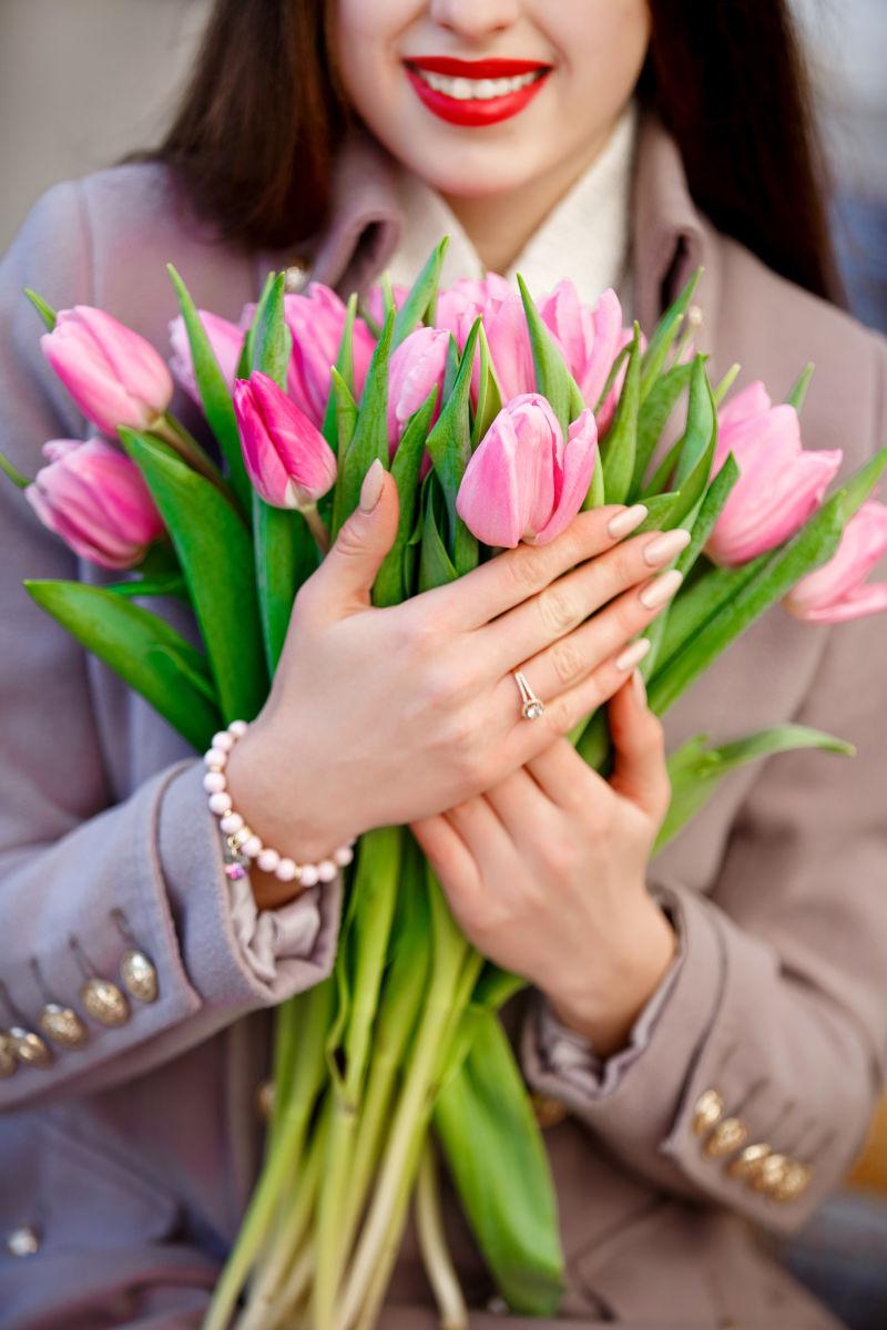 漂亮的女孩展示粉红色的郁金香花束