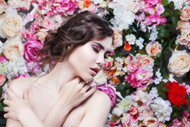 花朵背景下抱着肩膀闭着眼睛的性感美女