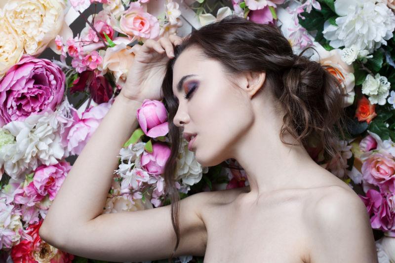 花墙前面闭着眼睛手抚摸头的年轻美女