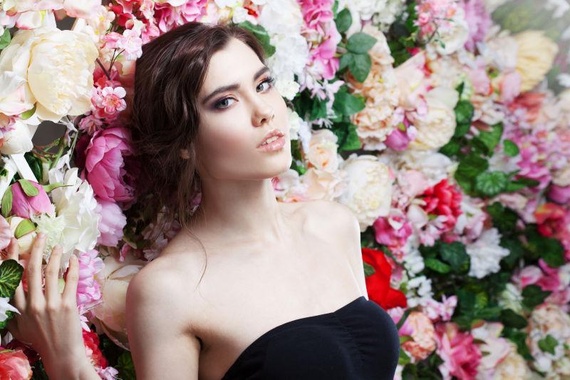 花墙前面穿着黑色抹胸的年轻美女