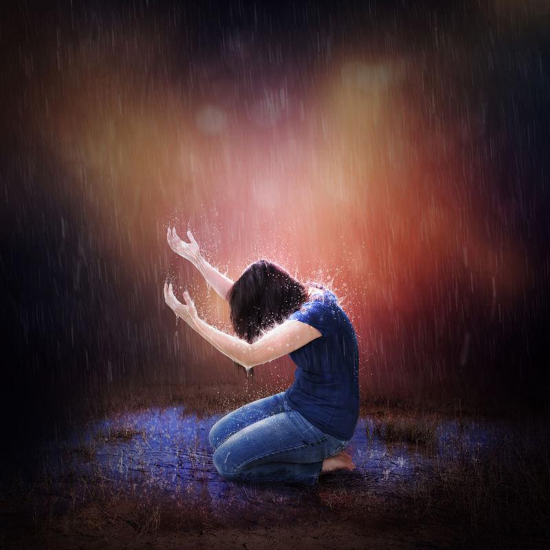 在大雨中跪着祈祷的女人
