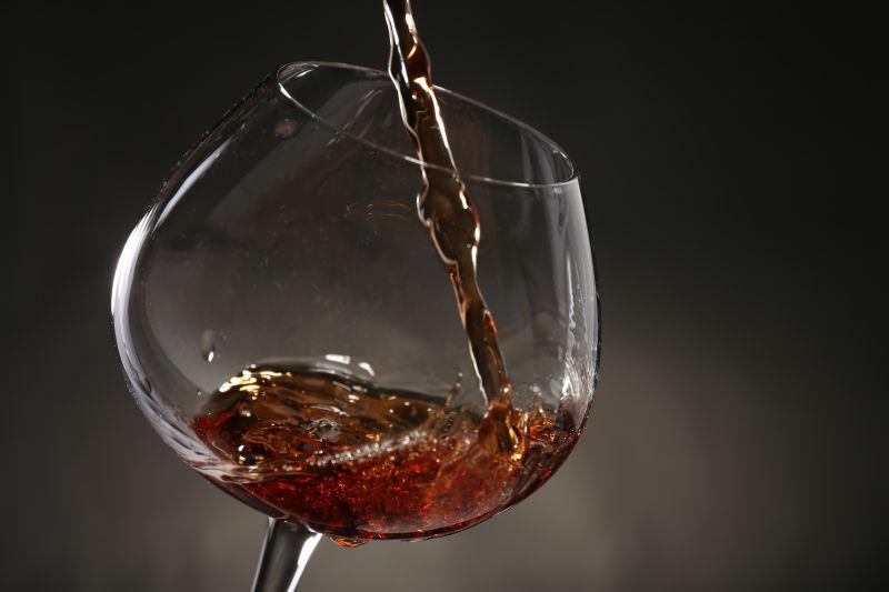 会黑色背景下向高脚杯中倒入红酒