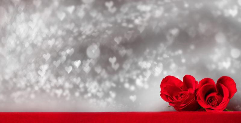 闪亮背景中的两朵心形玫瑰