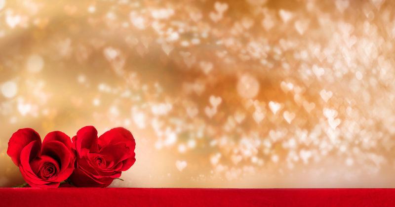 红色桌面上的两朵玫瑰花