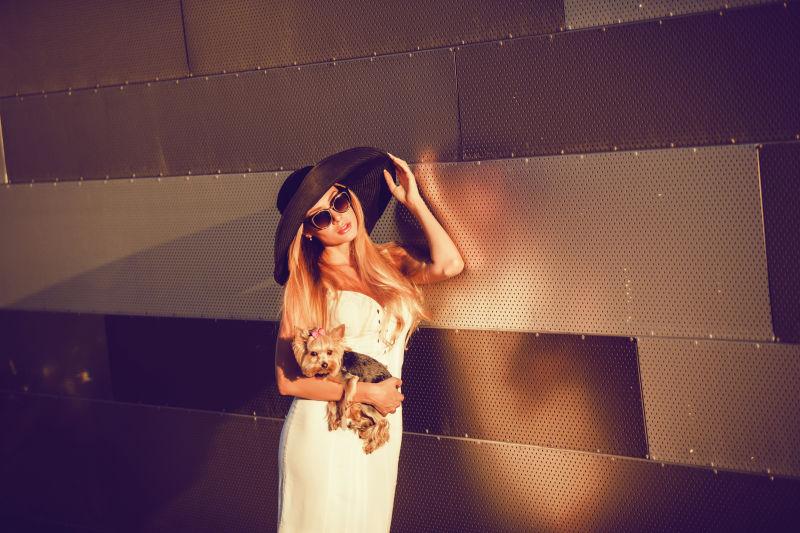 带着太阳眼镜抱着宠物狗的年轻美女