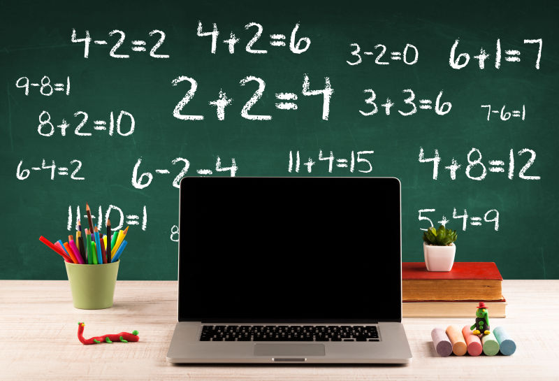 充满数字的黑板和学生课桌上的电脑